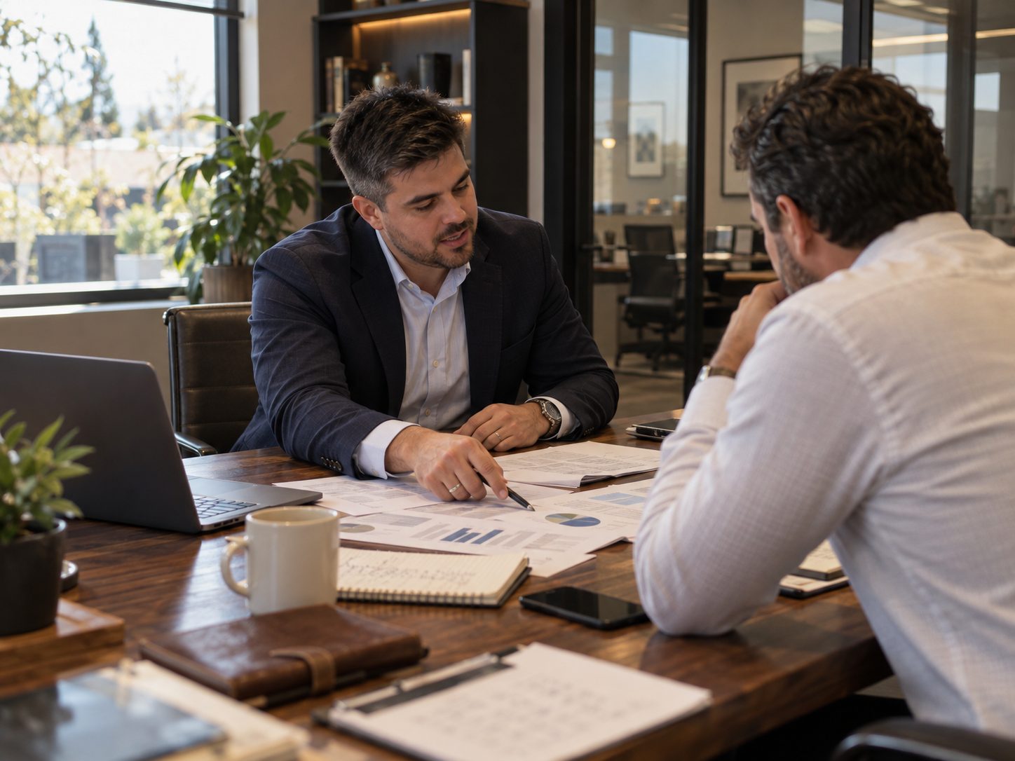 Pedro Monteiro reviewing performance reports with a business owner at a walnut table